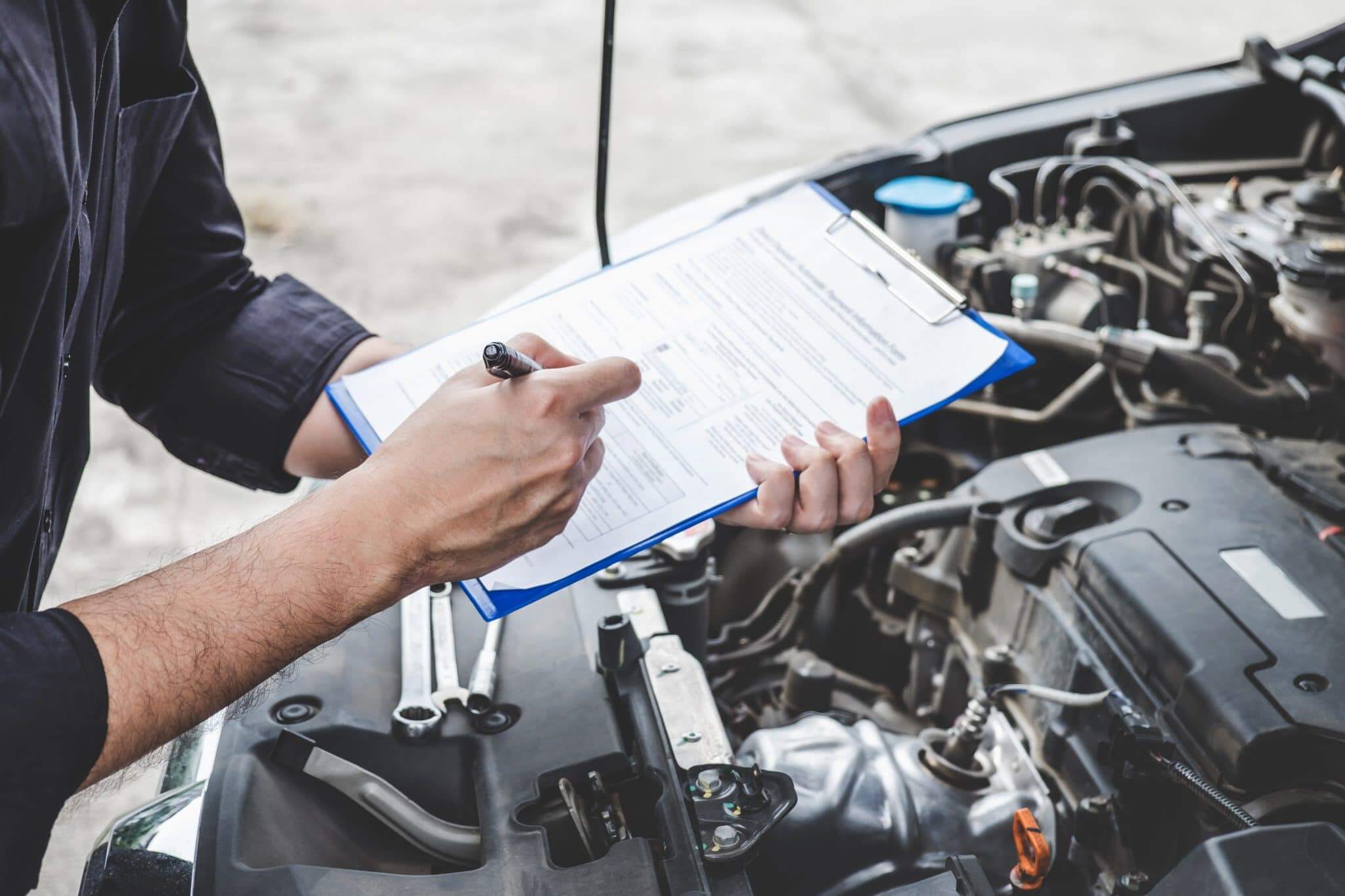 man holding clipboard with rv warranty information looking over an open hood
