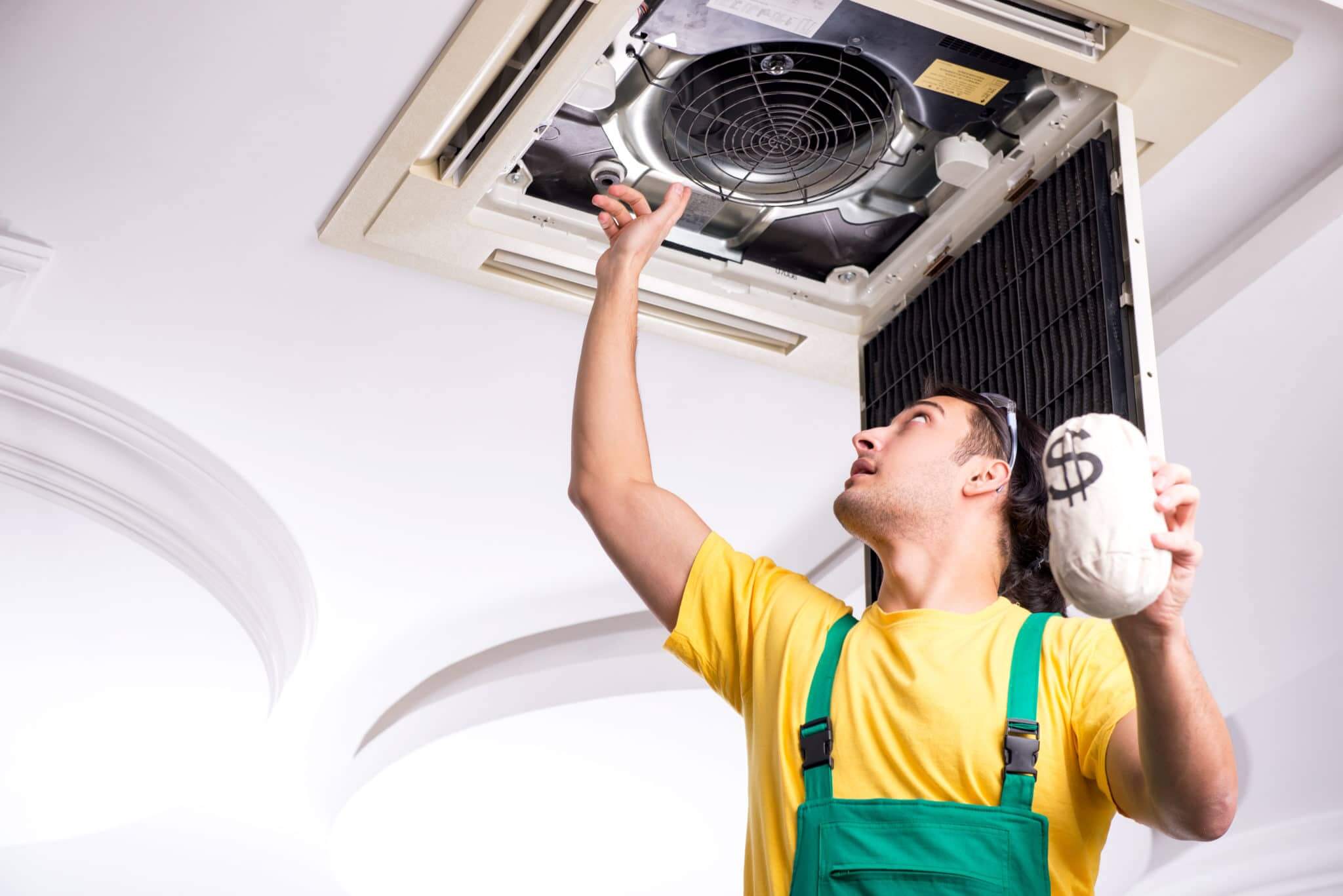 The young repairman repairing ceiling air conditioning unit