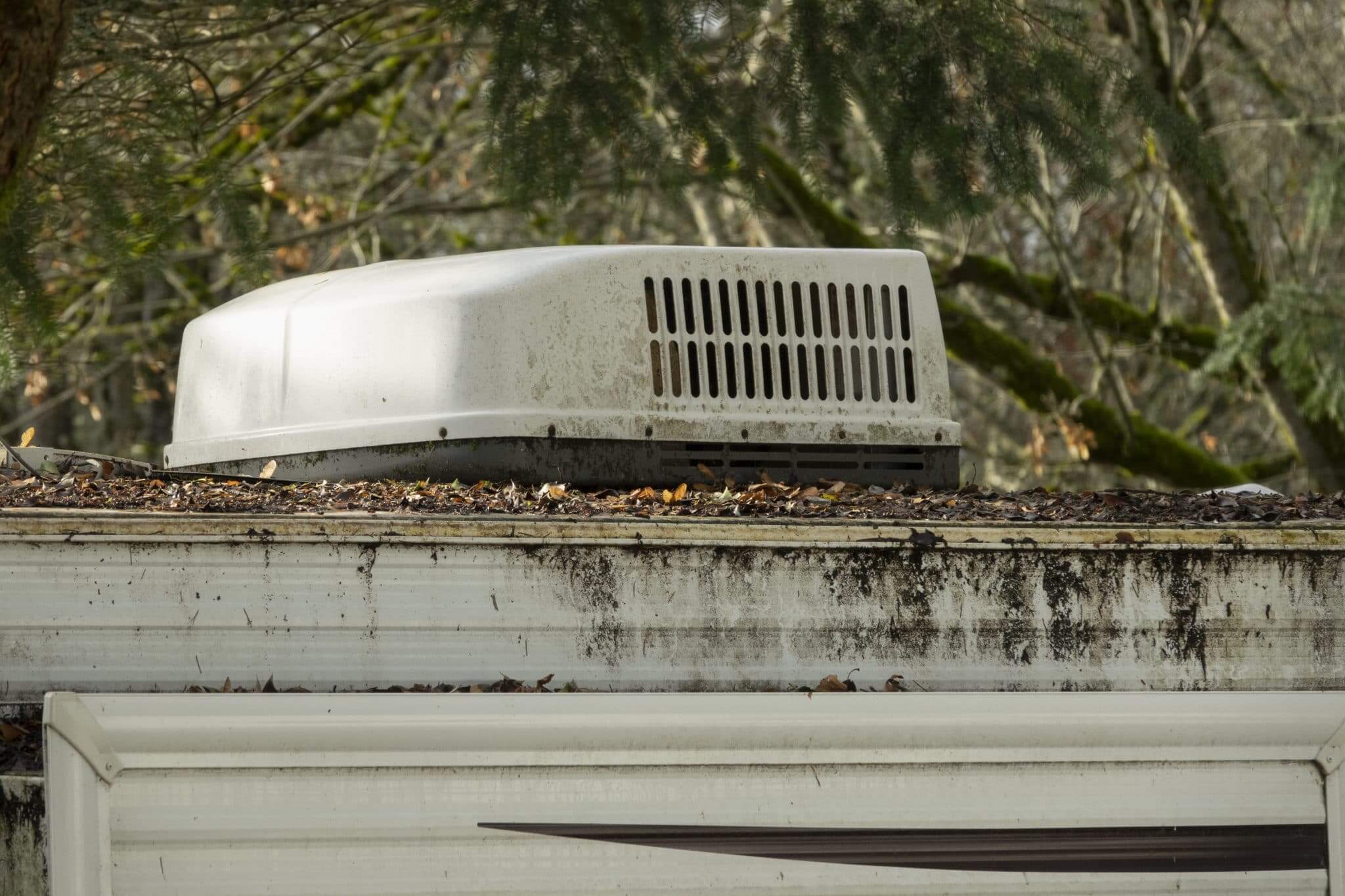 An AC unit on an old dirty recreational vehicle that needs some repair