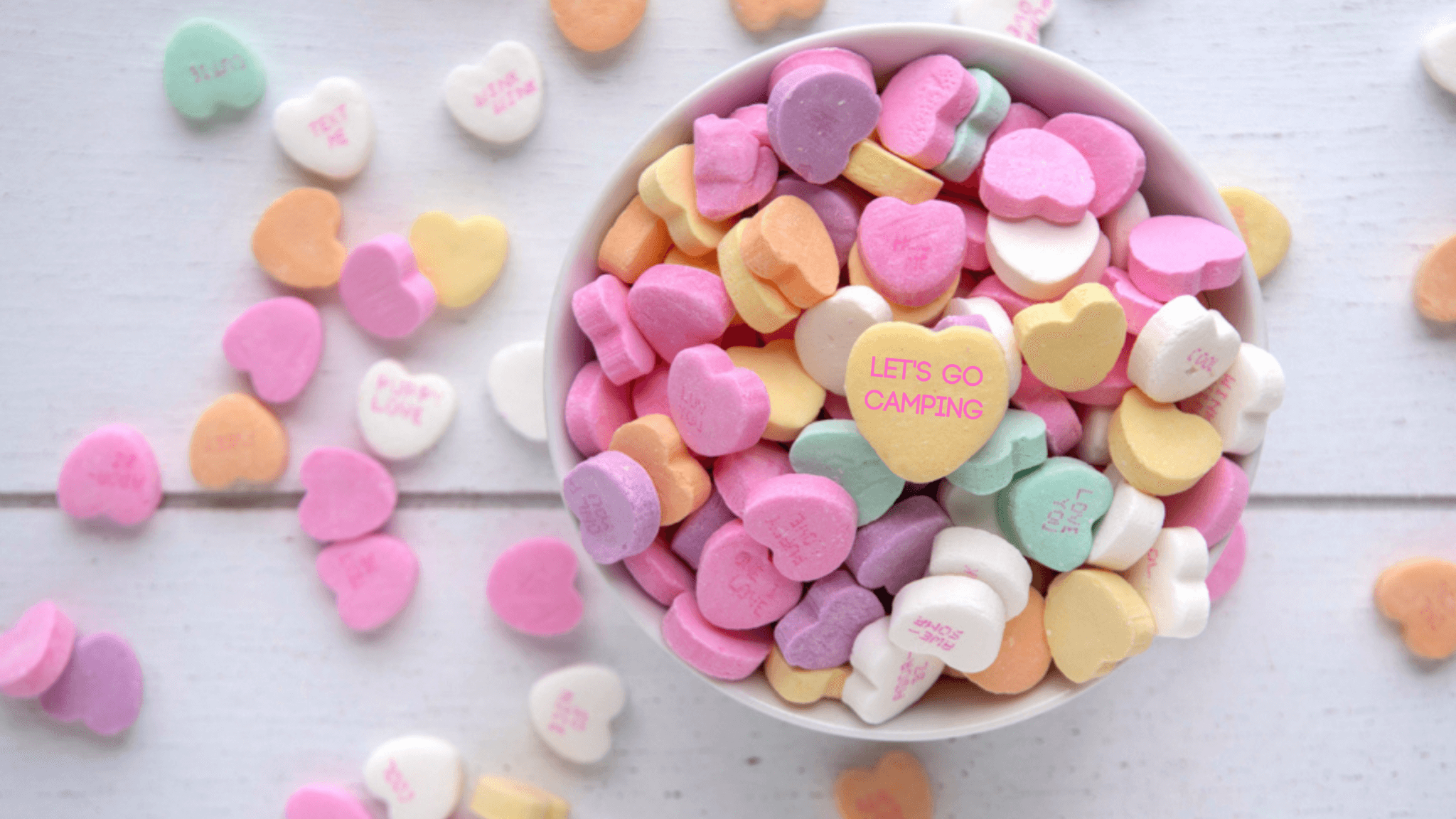 bowl of candy hearts on a table with the top candy saying "let's go camping". This covers Valentine gift ideas