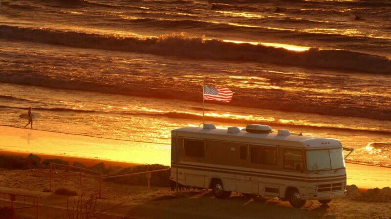 RV on beach flying a USA flag