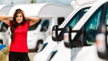 A woman with a red shirt stands in front of a row of RVs and she looks very stressed. Is 2021 the worst year to buy an RV?