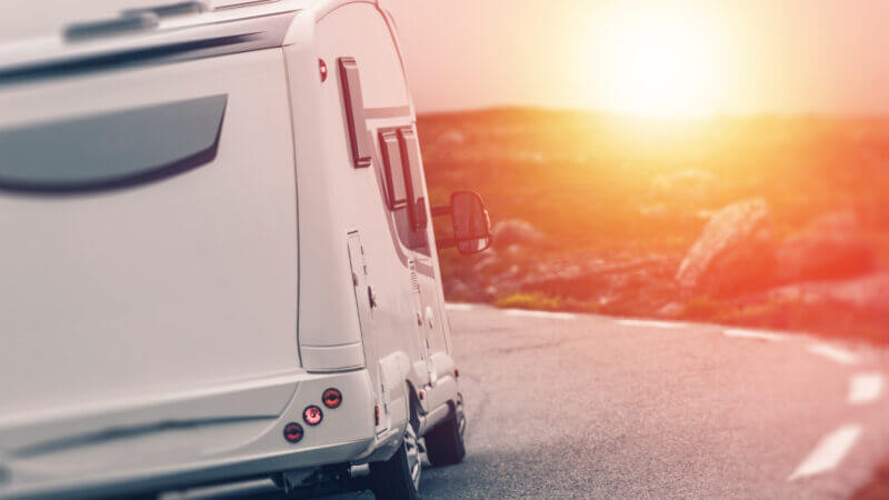 A really cool RV drives along the highway into the sunset.
