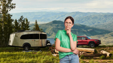 A woman stands in front of her campsite and ponders if her Airstream Basecamp trailer is worth the money.