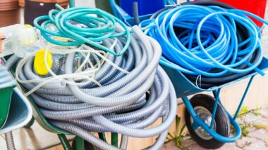 Several hoses thrown into wheel barrows in need of a storage solution.