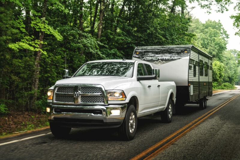 A white ram truck tows an Aspen model of a Dutchmen RV.