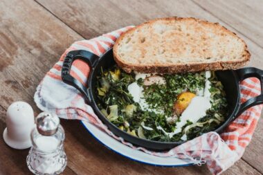 Toast and friend eggs in a cast iron skillet on a wooden table