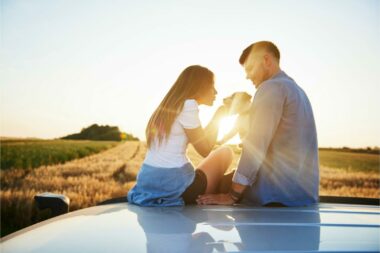 A couple sitting on top of their RV campervan with their pet dog