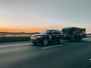 Black SUV pulling a car hauler trailer.
