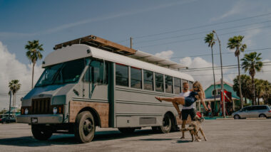 A couple by their skoolie bus.