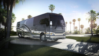 A Prevost RV outside by palm trees.