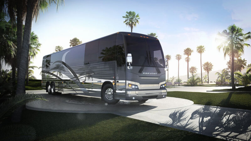 A Prevost RV outside by palm trees.
