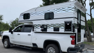 A white Capri Camper on a white truck outside.