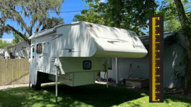 truck camper off truck with a measuring stick next to it