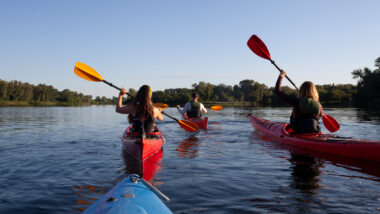 A group of friends kayaking after bringing their kayaks along using an RV kayak rack