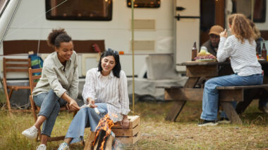 A group of friends having a good time eating after cooking with their toy hauler with outdoor kitchen