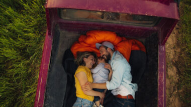 A couple laying in their truck bed with their child before adding a sleeping platform