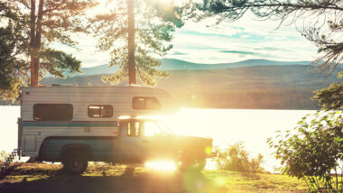 A truck camper parked by a lake