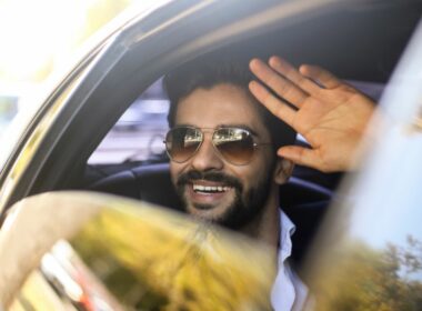 A celebrity waves out the window of a vehicle.