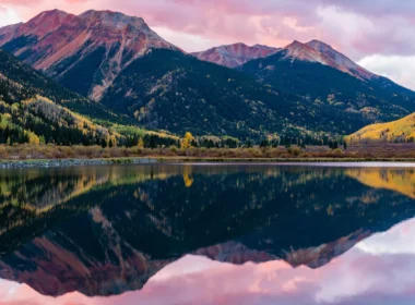 The rocky mountains with a lake beneath it and a purple dusky sky behind.