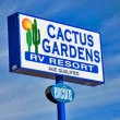 The Cactus Gardens RV Resort sign with a blue sky in the background, streaked with wispy clouds.