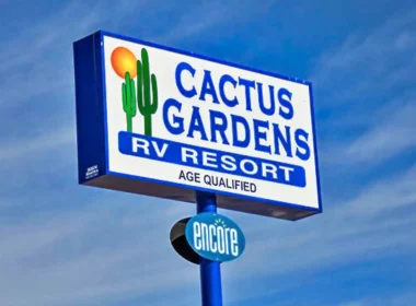 The Cactus Gardens RV Resort sign with a blue sky in the background, streaked with wispy clouds.