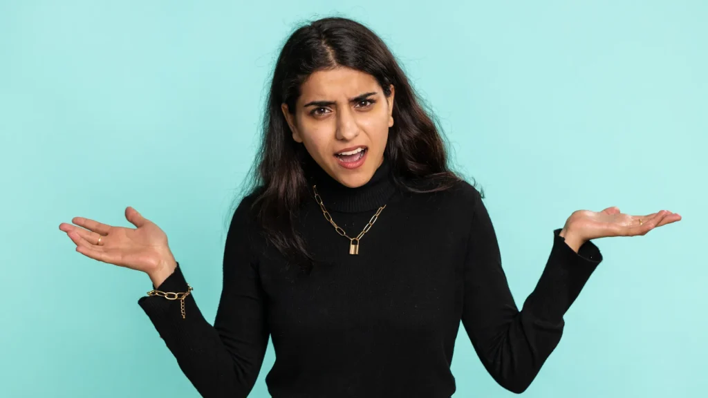 A person shrugging, gesturing "Why", against a blue background.
