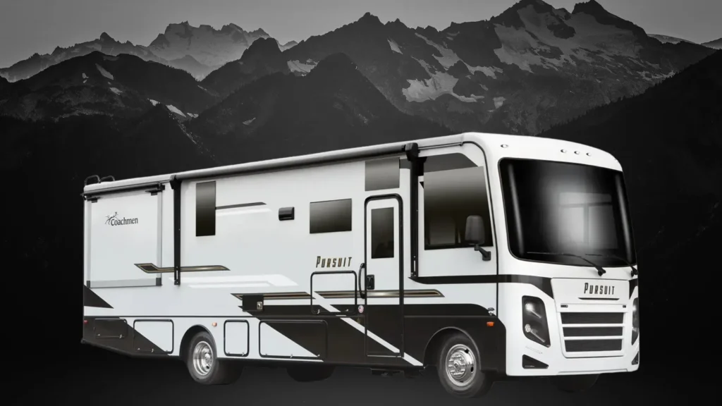 The exterior of the Coachmen Pursuit 27XPS as it sitsin front of a black and grey mountain range. 