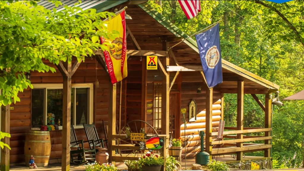 The KOA General store at their Fancy Gap location. Flags for KOA and Virginia are doned on the front of the wooden lodge. Wooden chairs, barrels, and other vintage decor sit along the front deck. 