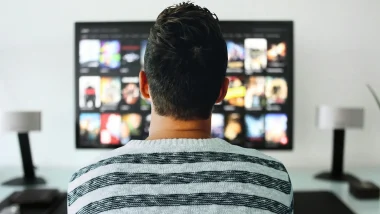 A person looking at their mounted TV on the wall, presumeably looking for something to watch as they sit seated.