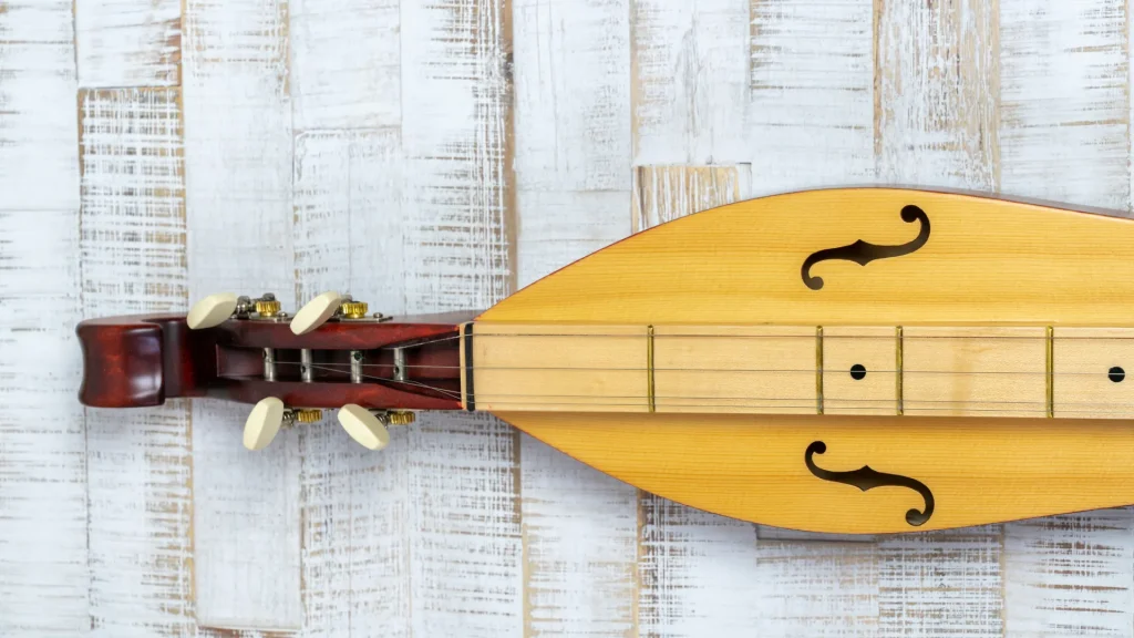 An Appalachian Mountain Dulcimer. A string instrument sittting atop a white-washed wooden table. 