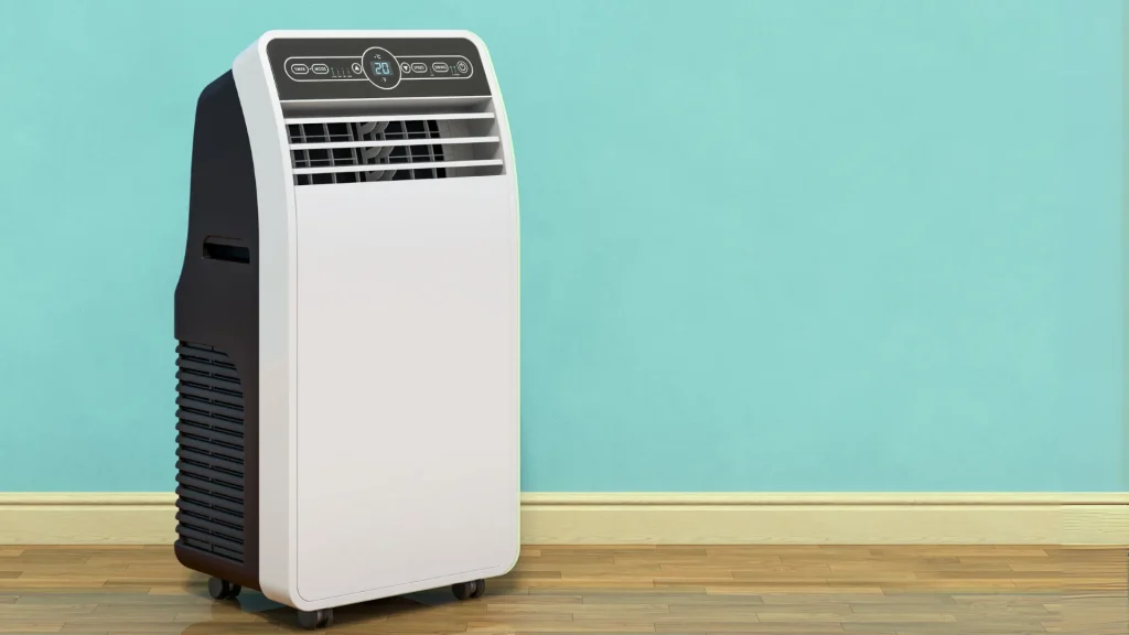 A white and black portable ac unit with a digital thermostat on a wooden floor with a teal blue wall in the background.