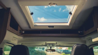 A skylight in a motorhome allowing sunlight to filter in as you can see the blue sky through it.