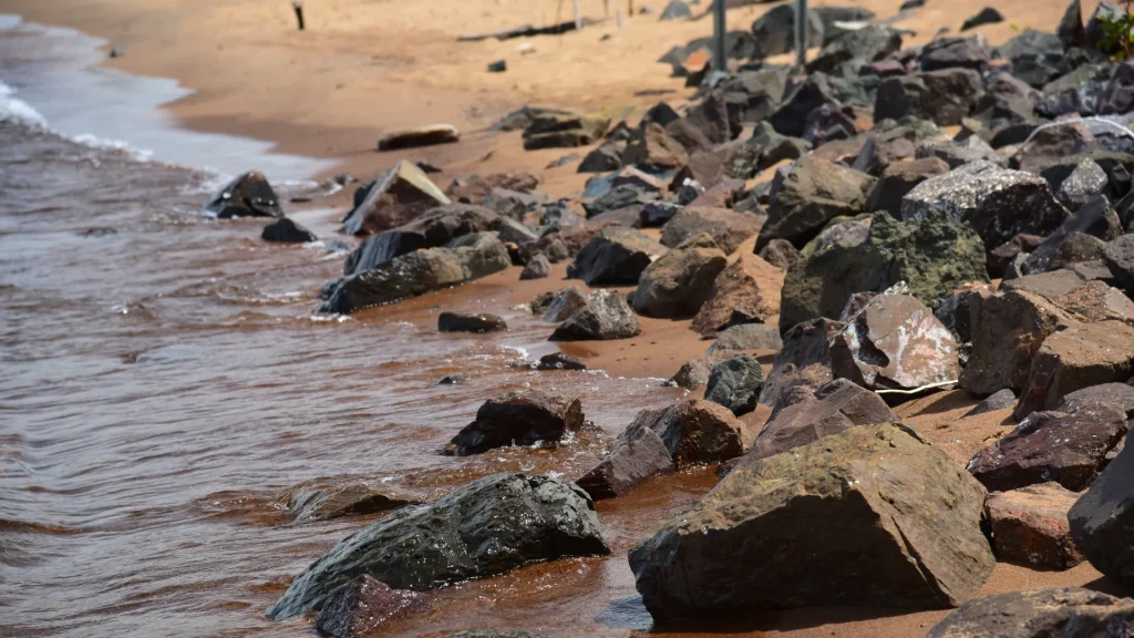 A rocky and sandy beach of the harbor in Copper Harbor, MI. It's a close up of the water and rocky beach.