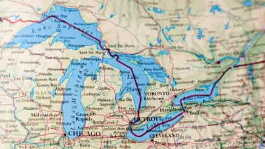 A map of the united states in beige and blue depicting the great lakes and the roadways, rivers, and lakes surround them.