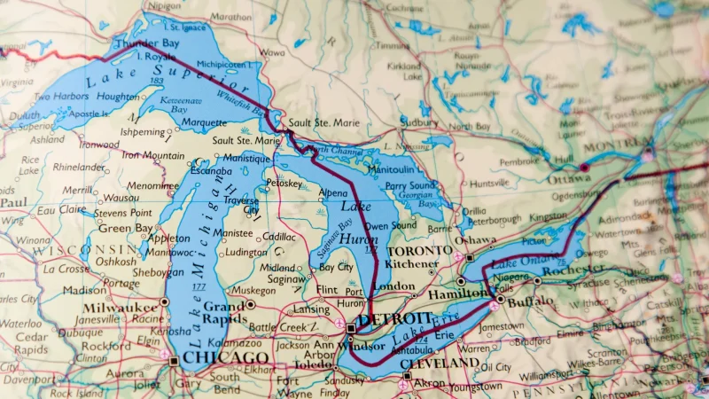 A map of the united states in beige and blue depicting the great lakes and the roadways, rivers, and lakes surround them.