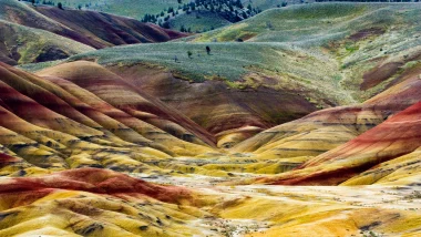 The Painted Hills in Oregon in colors of green, rusty reds, ochres, and oranges.