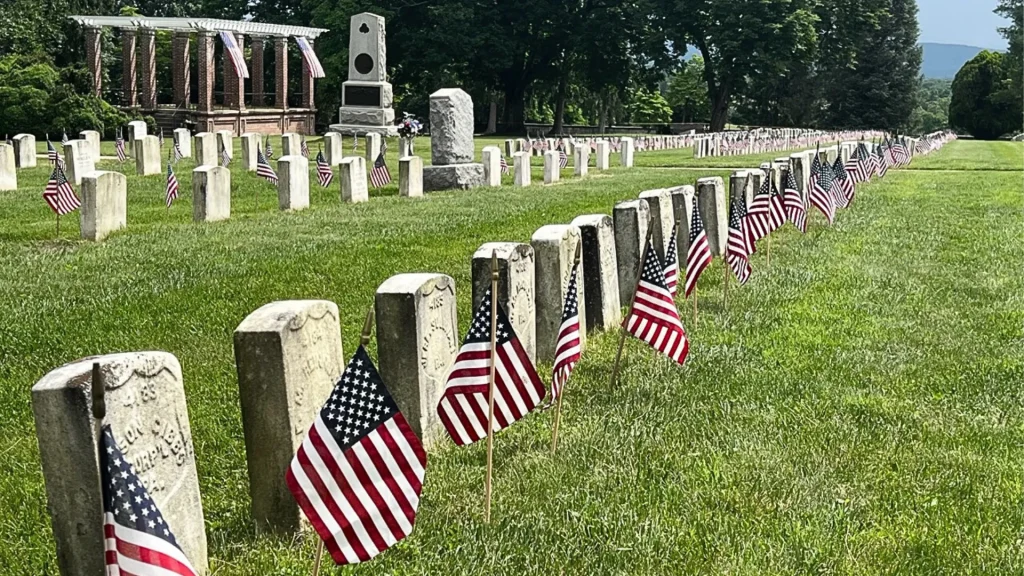 Antietam National Battlefield gravesite with American flag pendants stuck in the ground beside them for a commemoration on Memorial Day.