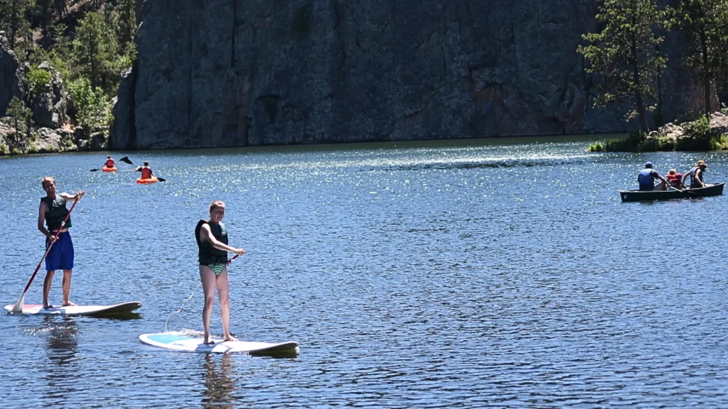 An image taken at Custer State Park as people enjoy recreational activities on the water (canoeing, paddle boarding, and kayaking).