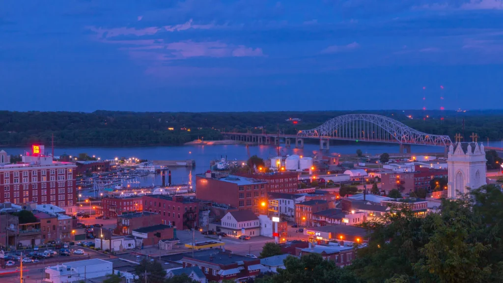 A night aerial photo of the city Dubuque, IA, as the city of lights glows a warm amber orange hue. 