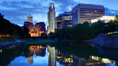 An image of the Lincoln, NE, skyline at night as lights reflect in the water below.