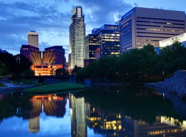 An image of the Lincoln, NE, skyline at night as lights reflect in the water below.