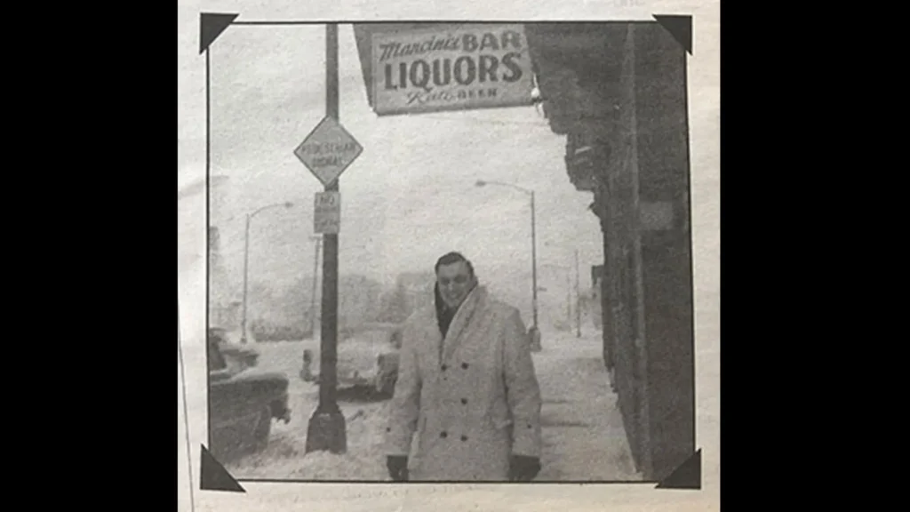 An old photo of Mancini's Char House of the owner standing beneath the sign on a snowy, cold day in Minnesota. ,