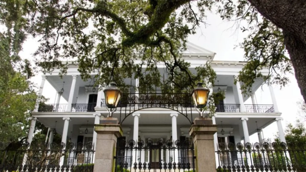 The exterior of the Buckner Mansion, which is white with a fence and gate around the property.