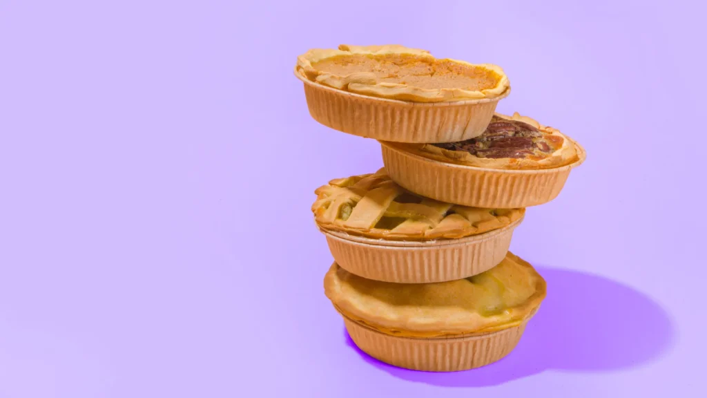 A stack of four pies against a purple backdrop.
