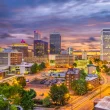Downtown Tulsa, OK, at night with a cloudy, dark sky. The city lights luminate the city.