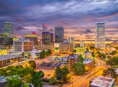 Downtown Tulsa, OK, at night with a cloudy, dark sky. The city lights luminate the city.
