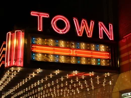 A theater sign lit up with bulbs and red neon as it says TOWN on the side of the overhang.