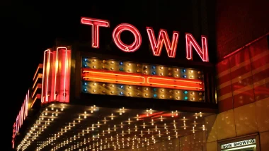 A theater sign lit up with bulbs and red neon as it says TOWN on the side of the overhang.