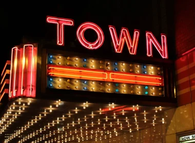 A theater sign lit up with bulbs and red neon as it says TOWN on the side of the overhang.